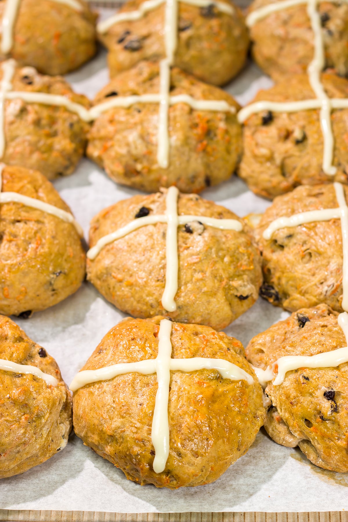Combine two favorite Easter recipes into one with these Carrot Cake Hot Cross Buns! These spiced buns includes carrots, raisins and chopped walnuts.