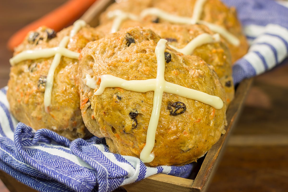 Combine two favorite Easter recipes into one with these Carrot Cake Hot Cross Buns! These spiced buns includes carrots, raisins and chopped walnuts.