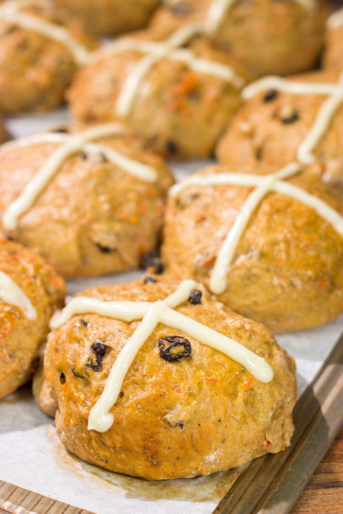 Combine two favorite Easter recipes into one with these Carrot Cake Hot Cross Buns! These spiced buns includes carrots, raisins and chopped walnuts.
