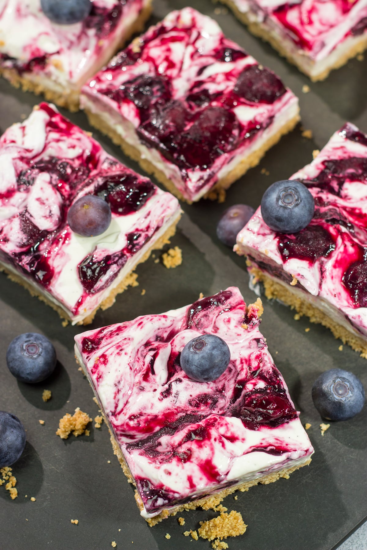 These No Bake Blueberry Cheesecake Bars feature a creamy cheesecake filling swirled with fresh blueberry jam on top of a buttery graham cracker crust. They're perfect for a hot summer day!