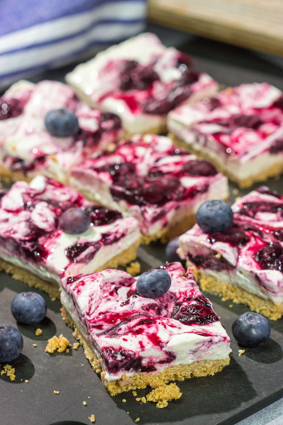 These No Bake Blueberry Cheesecake Bars feature a creamy cheesecake filling swirled with fresh blueberry jam on top of a buttery graham cracker crust. They're perfect for a hot summer day!