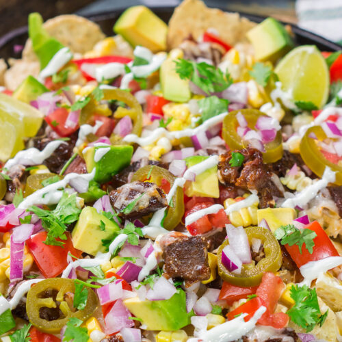 These Smoked Brisket Nachos are a great gameday appetizer! Crunchy tortilla chips topped with shredded cheese, smoked brisket and your favorite nacho toppings...yum!