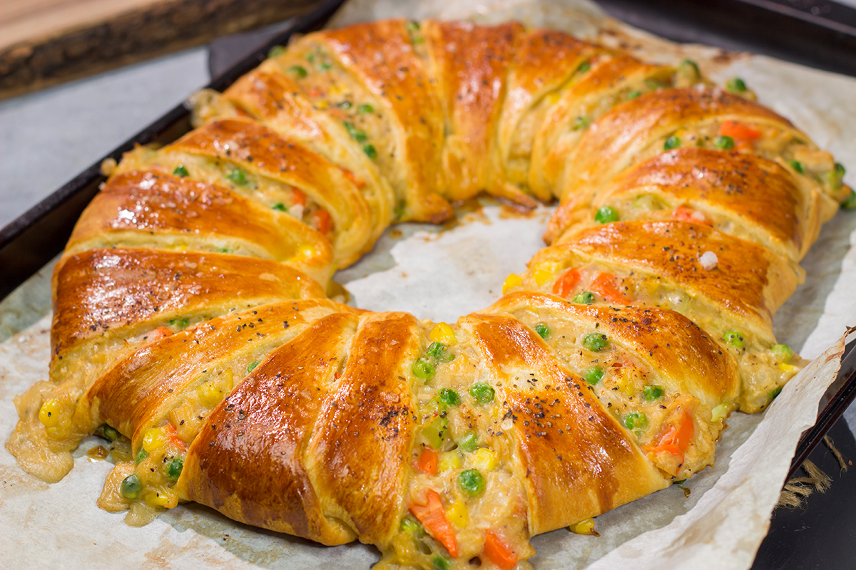 Put a unique spin on dinner with this Chicken Pot Pie Wreath! Homemade pot pie filling is wrapped in flaky crescent dough and shaped into a wreath for a fun take on a classic comfort food meal!