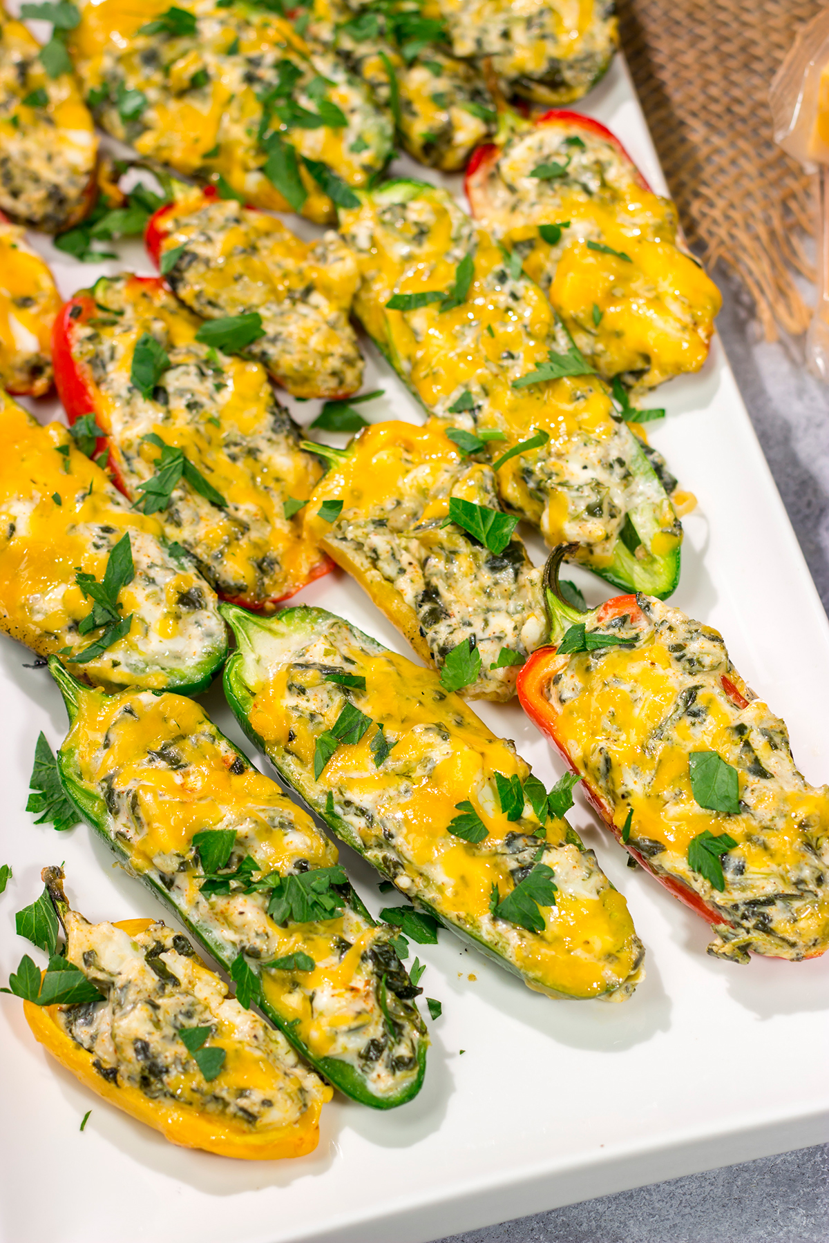 These Grilled Spinach Dip Stuffed Jalapenos feature peppers stuffed with creamy homemade spinach dip and topped with cheddar cheese. They're a delicious appetizer for summer grilling!