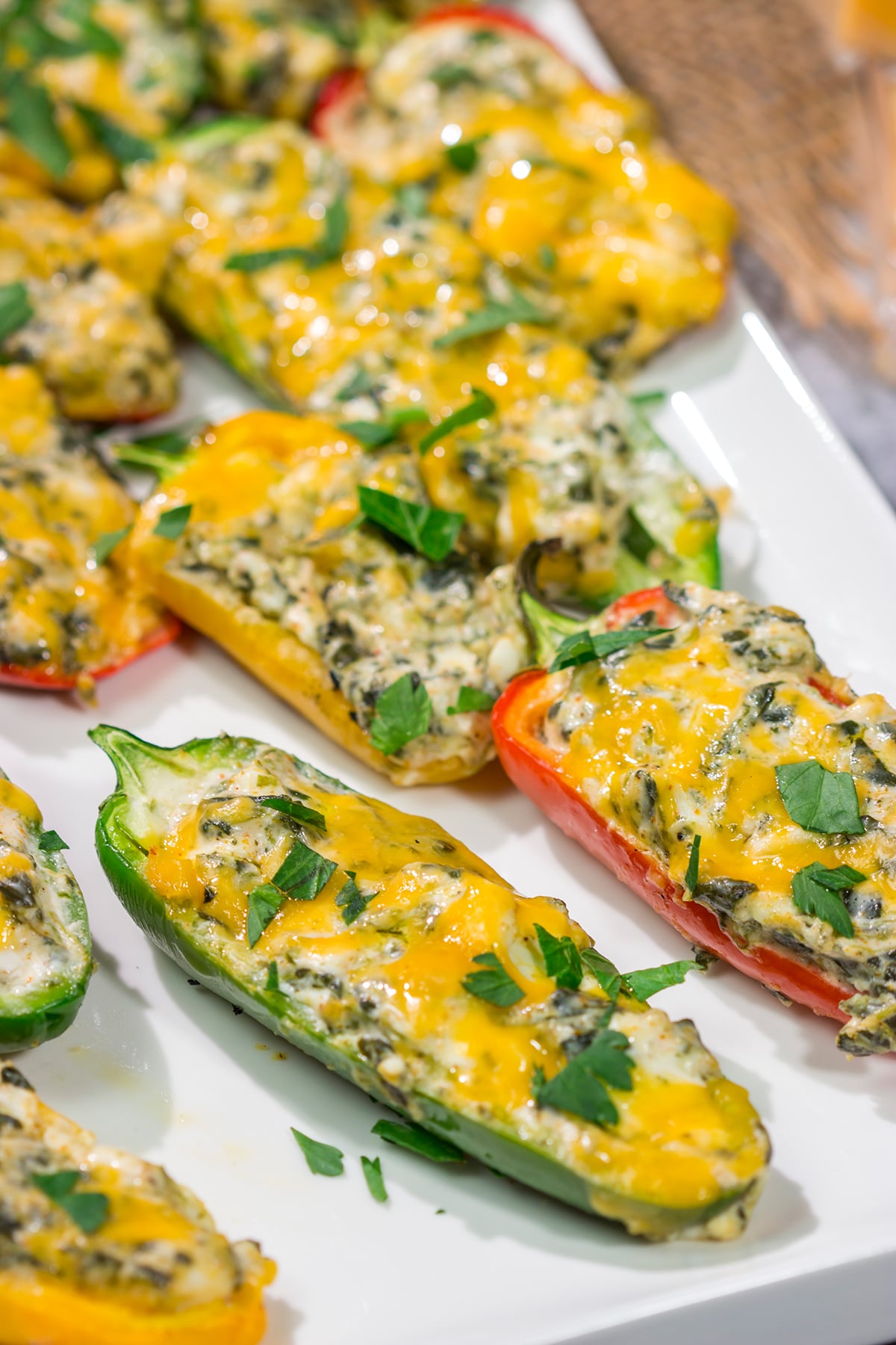 These Grilled Spinach Dip Stuffed Jalapenos feature peppers stuffed with creamy homemade spinach dip and topped with cheddar cheese. They're a delicious appetizer for summer grilling!